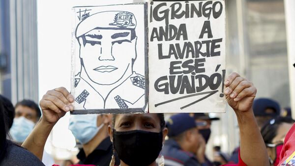 Una simpatizante del Gobierno del presidente Nicolás Maduro sostiene un cartel contra el líder opositor Juan Guaidó, afuera de la Asamblea Nacional, en Caracas, en 2021. - Sputnik Mundo