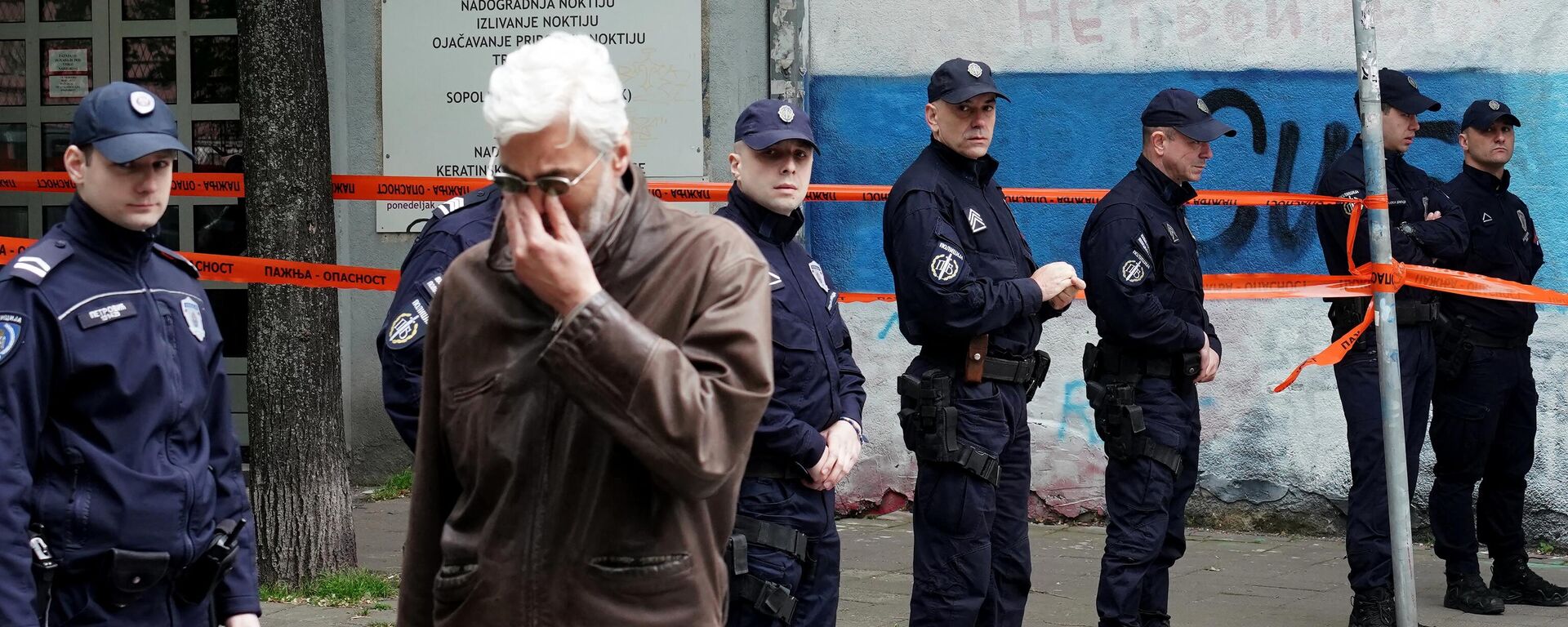 Un hombre llora mientras camina junto a los agentes de Policía que custodian la entrada de la escuela tras un tiroteo en una escuela de la capital, Belgrado, el 3 de mayo de 2023 - Sputnik Mundo, 1920, 03.05.2023