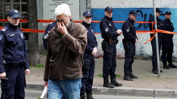 Un hombre llora mientras camina junto a los agentes de Policía que custodian la entrada de la escuela tras un tiroteo en una escuela de la capital, Belgrado, el 3 de mayo de 2023 - Sputnik Mundo