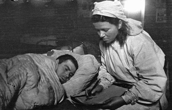 Una enfermera escribe una carta dictada por un soldado herido a su familia, febrero de 1944. - Sputnik Mundo