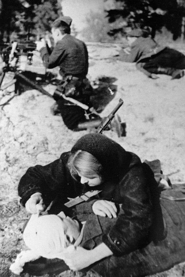 Una enfermera de una unidad partisana venda a un herido en plena batalla, Bielorrusia, abril de 1943. - Sputnik Mundo