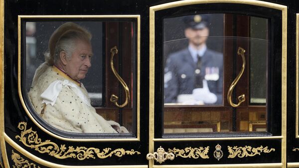 El rey Carlos III del Reino Unido y Camilla, la reina consorte, pasean en el coche de Estado del Jubileo de Diamante por delante del Palacio de Westminster de camino a su ceremonia de coronación, en Londres el sábado 6 de mayo de 2023 - Sputnik Mundo