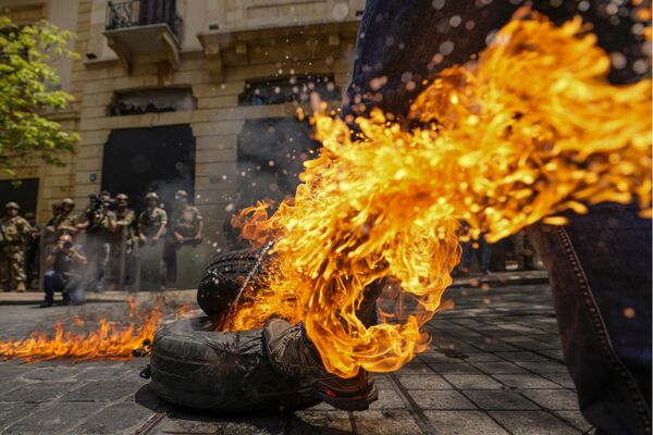 Un cliente de un banco defraudado junto a un neumático ardiendo durante las protestas masivas en el centro de Beirut, el Líbano. - Sputnik Mundo