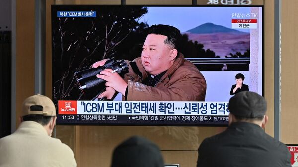 Varias personas observan una pantalla de televisión que muestra una imagen del líder de Corea del Norte, Kim Jong Un, presenciando el disparo de prueba de un misil balístico intercontinental Hwasong-17, en una estación de ferrocarril de Seúl, el 17 de marzo de 2023 - Sputnik Mundo