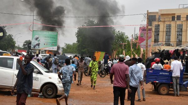 Vista general de una nube de humo mientras partidarios de las fuerzas de defensa y seguridad nigerianas atacan la sede del Partido Nigeriano para la Democracia y el Socialismo (PNDS), el partido del derrocado presidente Mohamed Bazoum, en Niamey, el 27 de julio de 2023.  - Sputnik Mundo