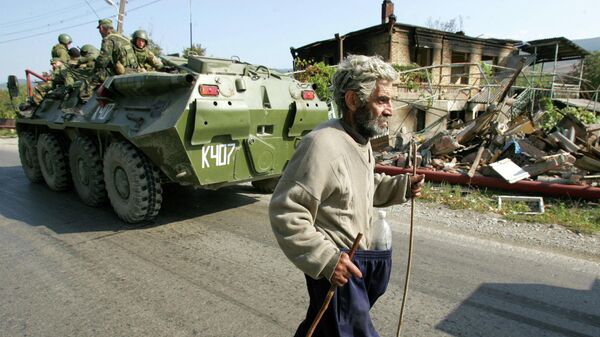 El residente pasa junto a tropas rusas en un vehículo blindado de transporte de tropas y edificios destruidos en Kurta, 20 kms al norte de Tsjinvali, Osetia del Sur, el 5 de septiembre de 2008. - Sputnik Mundo