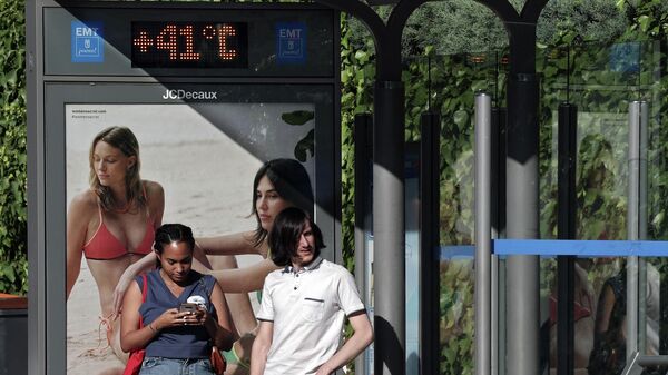 Personas esperan el autobús en una parada con un termómetro que marca 41 grados centígrados en Madrid, el 7 de julio de 2023  - Sputnik Mundo