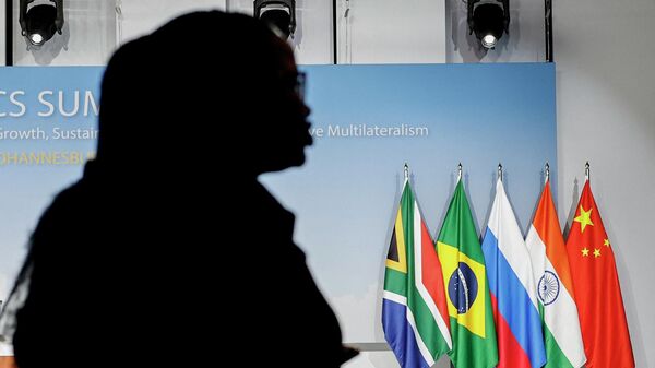 Una mujer junto a las banderas de Sudáfrica, Brasil, Rusia, India y China durante la Cumbre de los BRICS de 2023, en Johannesburgo, el 24 de agosto de 2023 - Sputnik Mundo