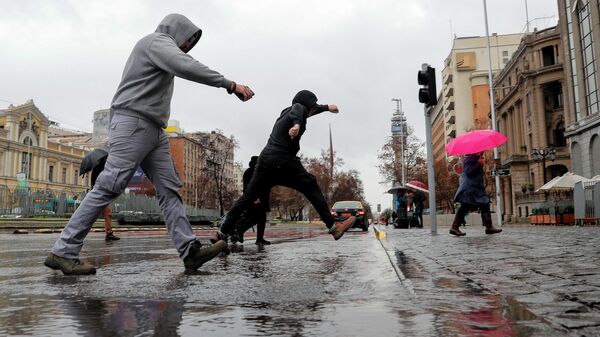 Personas saltan sobre un charco en Santiago, el 23 de agosto de 2023  - Sputnik Mundo
