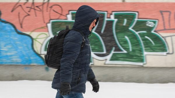 Un hombre camina mientras cae la nieve en Riga  - Sputnik Mundo