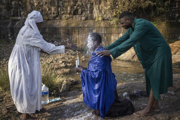 Una mujer vierte leche sobre la cabeza de otro devoto durante un ritual de purificación en un parque de Johannesburgo, Sudáfrica.   - Sputnik Mundo