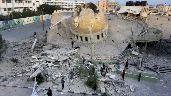 Un grupo de personas frente a una mezquita destruida por un ataque aéreo israelí en Jan Younis, Franja de Gaza, el domingo 8 de octubre de 2023. - Sputnik Mundo