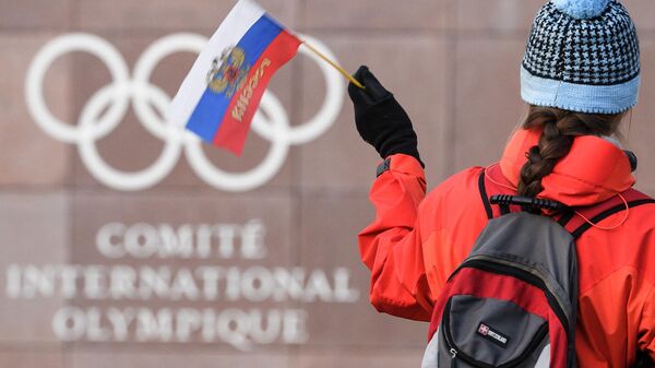 Un aficionado ondea una bandera rusa delante del logotipo del Comité Olímpico Internacional. - Sputnik Mundo