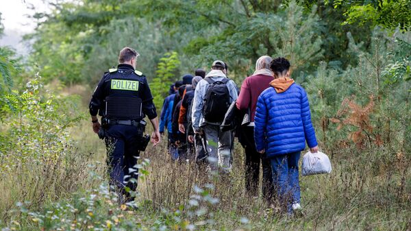 Un agente de la Policía Federal alemana escolta a un grupo de migrantes cerca de Forst, en el este de Alemania - Sputnik Mundo