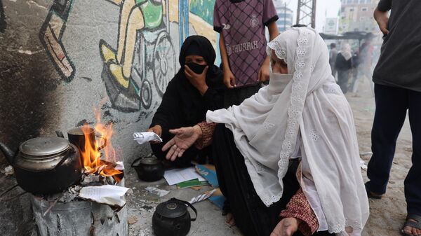 Женщина разжигает бумагой огонь, чтобы нагреть воду для чая, в Рафахе на юге сектора Газа - Sputnik Mundo