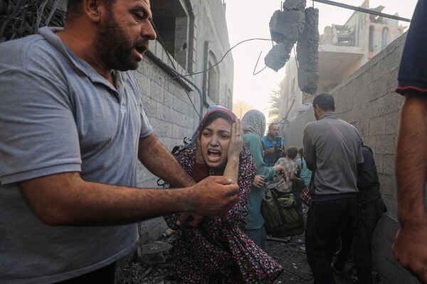 Palestinos conmocionados tras un bombardeo israelí en las afueras del campo de refugiados de Maghazi, en el centro de la Franja de Gaza. Palestinos conmocionados tras un bombardeo israelí en las afueras del campo de refugiados de Maghazi, en el centro de la Franja de Gaza. - Sputnik Mundo