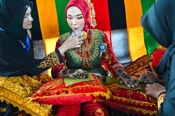 Una concursante durante la Semana Cultural de Aceh aplica en las manos de una modelo un patrón tradicional de henna, que se hace para las novias en la región. - Sputnik Mundo