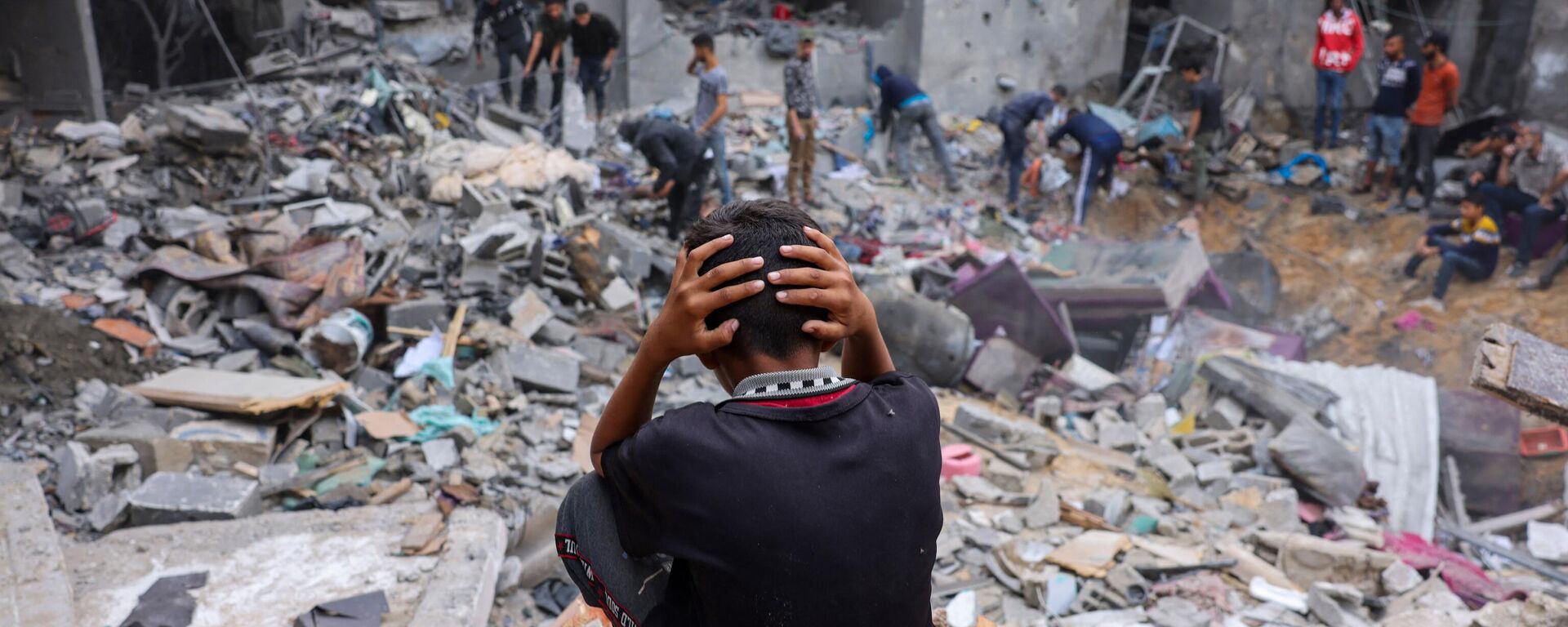 Un niño reacciona mientras la gente rescata pertenencias entre los escombros de un edificio dañado tras los ataques contra Rafah, en el sur de la Franja de Gaza, el 12 de noviembre de 2023  - Sputnik Mundo, 1920, 29.11.2023
