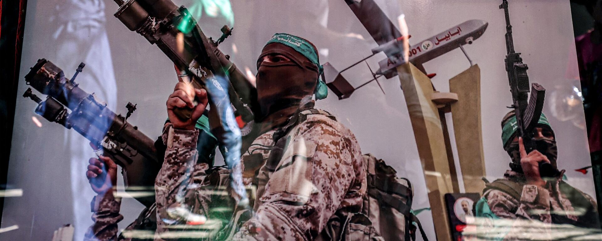 Un reflejo muestra a la gente caminando junto a un cartel en un escaparate que muestra a un combatiente de las Brigadas al-Qassam, el ala militar de Hamás. - Sputnik Mundo, 1920, 19.11.2023