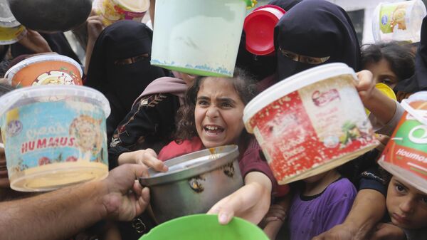 Palestinos hacen fila  para conseguir alimentos durante el bombardeo israelí de la Franja de Gaza en Rafah.  - Sputnik Mundo
