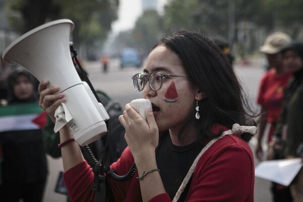 Una mujer con la cara pintada de sandía grita consignas por un megáfono durante una protesta en solidaridad con el pueblo palestino frente a la Embajada estadounidense en Yakarta el 9 de noviembre de 2023. - Sputnik Mundo
