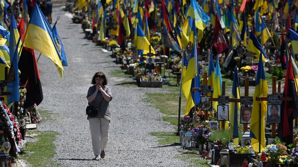 Una mujer pasa por un cementerio ucraniano - Sputnik Mundo