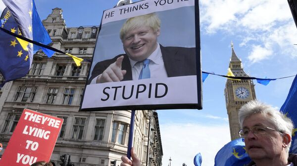 Manifestantes muestran pancartas con el ex primer ministro británico Boris Johnson  - Sputnik Mundo