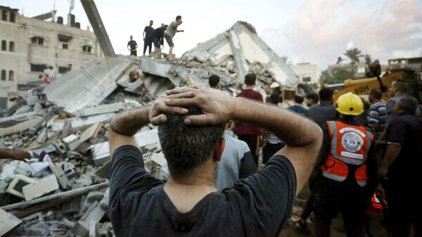 Un hombre reacciona mientras observa cómo socorristas y civiles retiran los escombros de una vivienda destruida tras un ataque israelí contra la ciudad de Deir Al Balah, en el centro de la Franja de Gaza, el 15 de octubre de 2023  - Sputnik Mundo