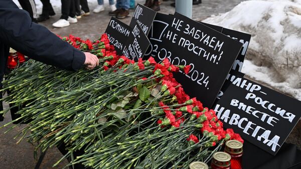 Varias personas llevan flores al lugar del bombardeo ucraniano de una panadería en Lisichansk - Sputnik Mundo