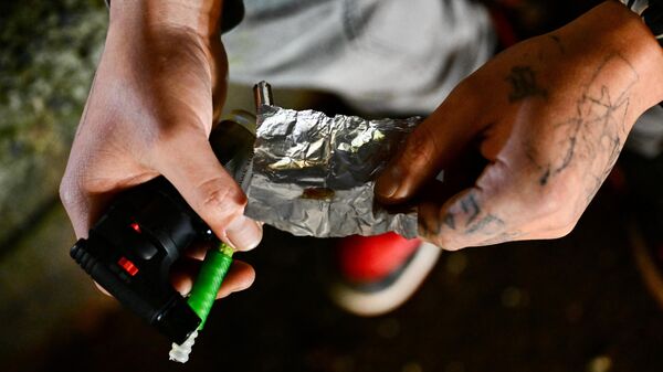 Una persona sostiene un papel de aluminio mientras fuma fentanilo en Park Avenue tras la despenalización de todas las drogas en el centro de Portland, Oregón, el 23 de enero de 2024. - Sputnik Mundo