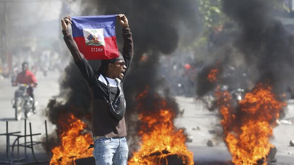 Un manifestante sostiene una bandera haitiana durante las protestas que exigen la dimisión del primer ministro Ariel Henry en Puerto Príncipe, Haití, el 1 de marzo de 2024 - Sputnik Mundo