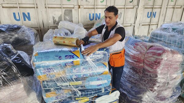 Un trabajador de Naciones Unidas preparando la ayuda para su distribución a los palestinos  - Sputnik Mundo