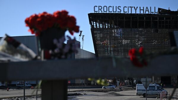 Flores a lo largo de la carretera cerca del edificio de la sala de conciertos Crocus City Hall en memoria de las víctimas del ataque terrorista del 22 de marzo, 2024 - Sputnik Mundo