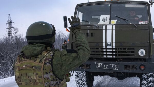A Donetsk militia signals for a Ukrainian convoy truck to stop on the road near the Airport of Donetsk - Sputnik Mundo