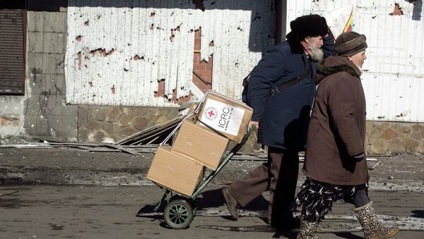 A man walking with a woman pulls a trolley with International Committee of the Red Cross relief packages in the town of Debaltseve February 22, 2015 - Sputnik Mundo