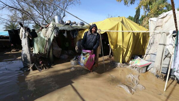 Palestinian man salvages his belongings from his dwelling after it was flooded by rain water - Sputnik Mundo
