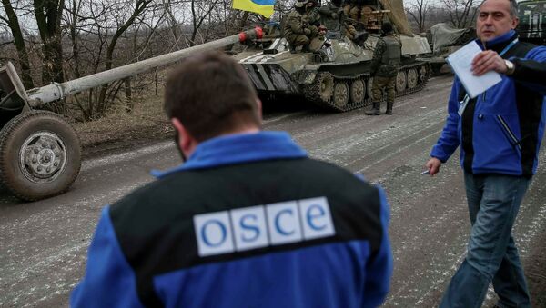Members of Special Monitoring Mission of the Organization for Security and Cooperation (OSCE) to Ukraine walk along a convoy of Ukrainian armed forces in Paraskoviyvka, eastern Ukraine - Sputnik Mundo