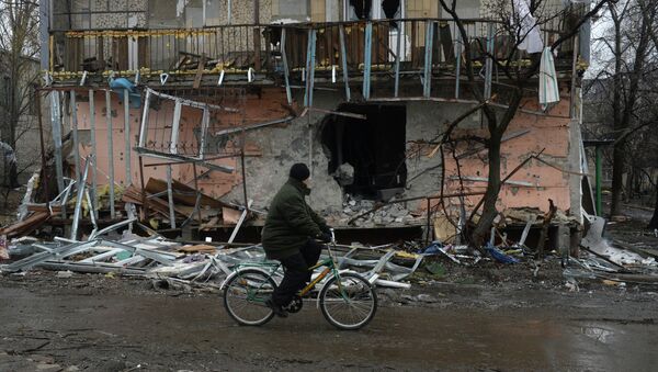 Житель города Дебальцево едет на велосипеде мимо разрушенного в результате обстрелов во время боевых действий жилого дома. - Sputnik Mundo