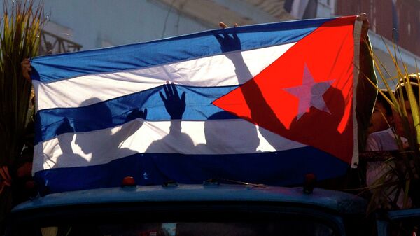 Children's shadows are cast on a Cuban national flag as they take part in a caravan tribute marking the 56th anniversary of the original street party that greeted a triumphant Castro and his rebel army, in Regla, Cuba, Thursday, Jan. 8, 2015 - Sputnik Mundo
