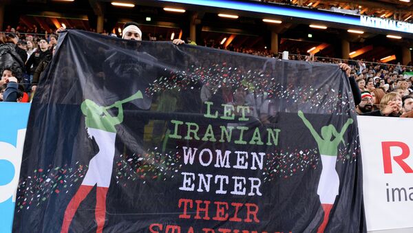 Hinchas sostienen una pancarta que dice 'Que las mujeres iraníes entren en sus estadios' durante el partido amistoso de fútbol entre Suecia e Irán - Sputnik Mundo