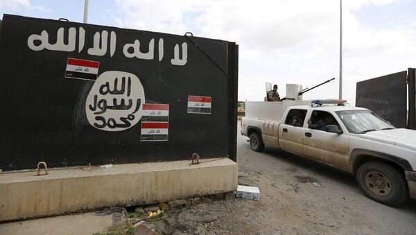 Iraqi security forces ride a vehicle past a wall painted with the black flag commonly used by Islamic State militants, near former Iraqi president Saddam Hussein's palace in Tikrit April 1, 2015 - Sputnik Mundo