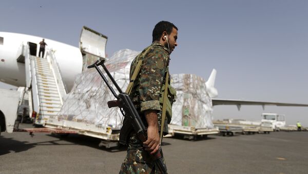 A Houthi militant walks past a shipment of emergency medical aid for the Red Cross being unloaded from a plane at Sanaa airport April 11, 2015. - Sputnik Mundo