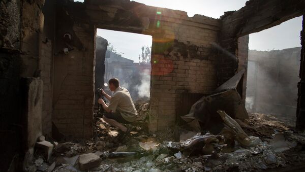 Periodista trabaja cerca de una casa destruida tras un ataque en el pueblo Semionovka, este de Ucrania - Sputnik Mundo