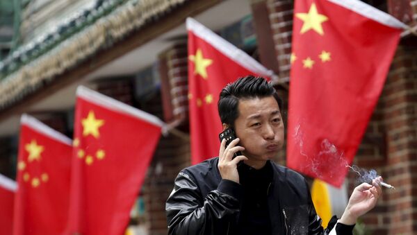A smoker walks past Chinese national flags in front of a restaurant in Beijing, China, May 11, 2015 - Sputnik Mundo