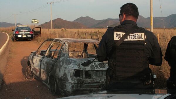 Federal police stand next to a bullet riddled and burned car after a criminal gang ambushed a police convoy near the town of Soyatlan, near Puerto Vallarta - Sputnik Mundo