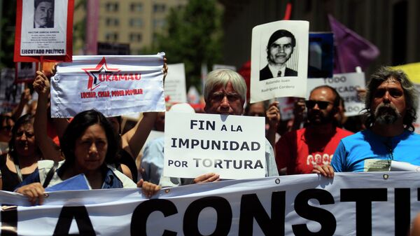 Manifestantes mantienen carteles con fotos de víctimas de la dictadura de Augusto Pinochet - Sputnik Mundo