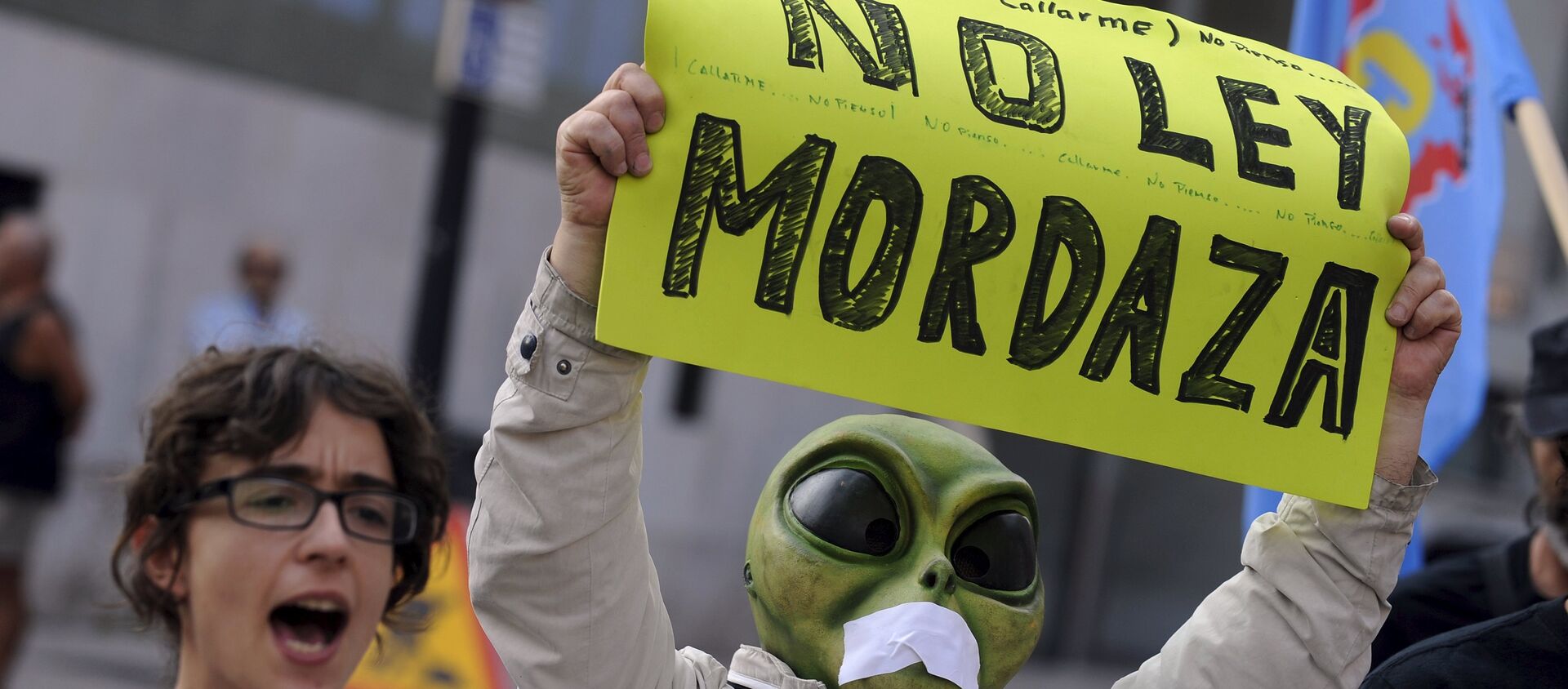 A man wearing a mask with a tape over the mouth holds up a sign during a protest against the Spanish government's new security law in Gijon, northern Spain, June 30, 2015. - Sputnik Mundo, 1920, 24.05.2016