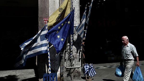 Un hombre camina delante de las banderas de UE y Grecia en el centro de Atenas. 13 de julio de 2015 - Sputnik Mundo