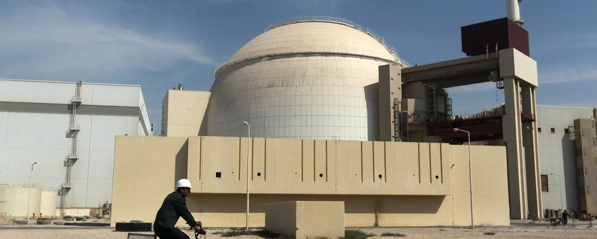 In this Oct. 26, 2010 file photo, a worker rides a bicycle in front of the reactor building of the Bushehr nuclear power plant, just outside the southern city of Bushehr. - Sputnik Mundo, 1920, 17.02.2021