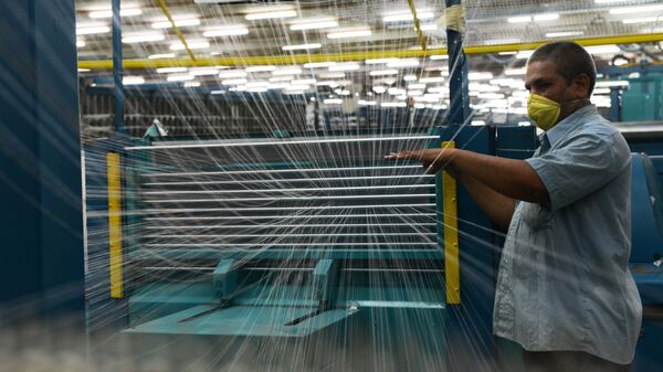 In this photograph taken on July 8, 2014 an Indian employee works at a textile factory in Khatraj village, some 20 kms from Ahmedabad. - Sputnik Mundo